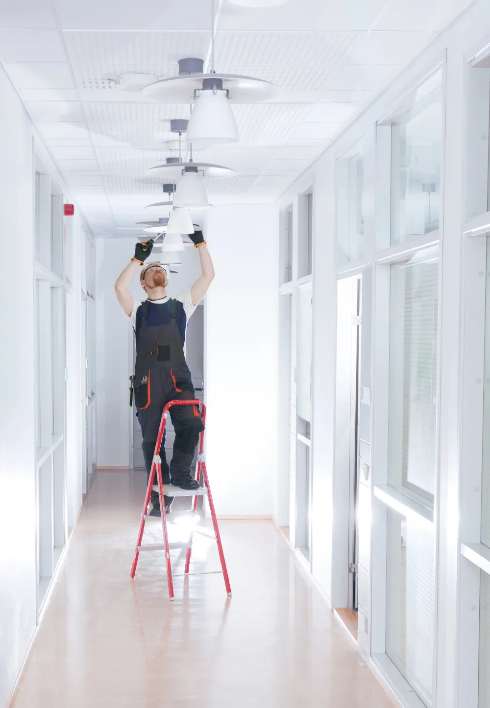 A repairman replacing a lightbulb on a ladder