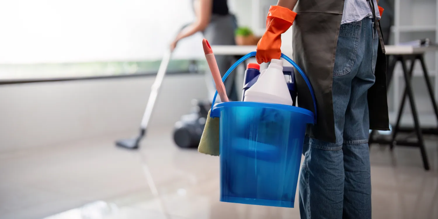 A cleaning man carrying a caddy of products