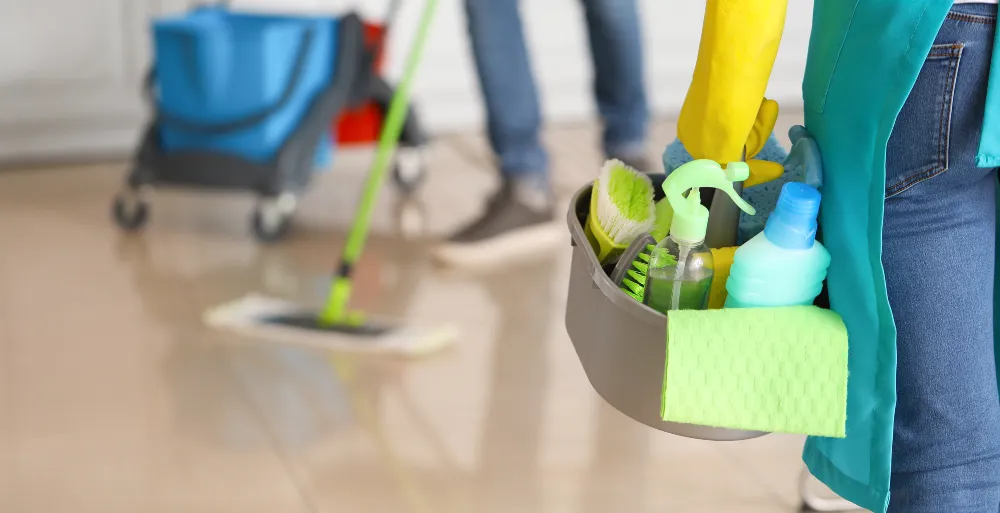 Cleaning woman carrying a caddy of disinfecting products