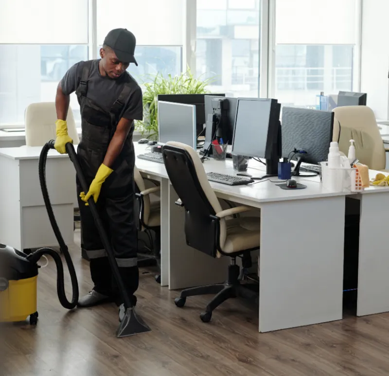 Male cleaner vacuuming office floor